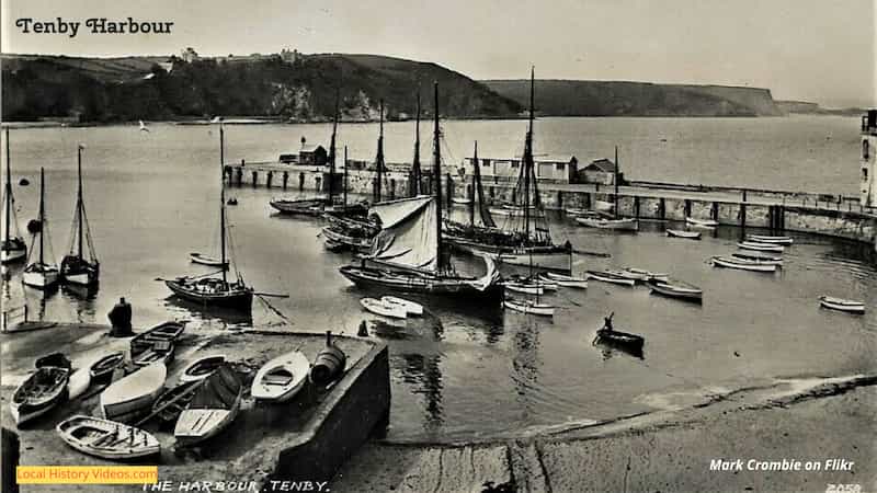 Old postcard of a man rowing out to fishing boats at Tenby Harbour