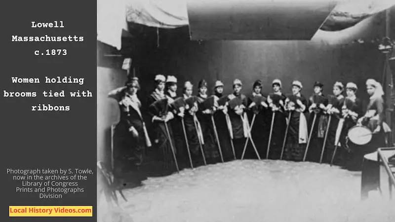 Old photo, taken by S. Towle around 1873, of a group of women holding brooms ties with ribbons
