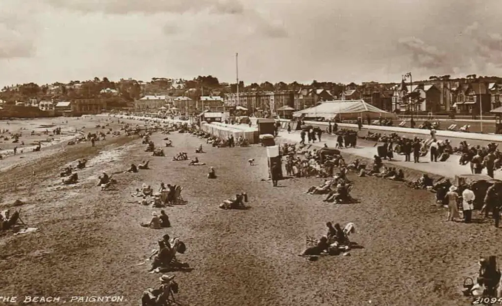 Old photo postcard of the beach at Paignton in Devon, England, including the Punch and Judy booth entertaining children